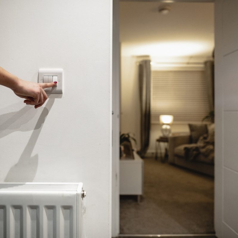 Unrecognisable woman with her finger on a light switch turning lights off.